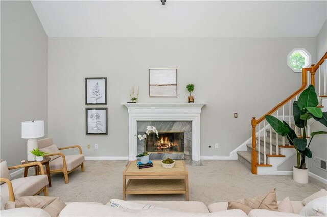 living area featuring carpet floors, stairs, visible vents, and a premium fireplace