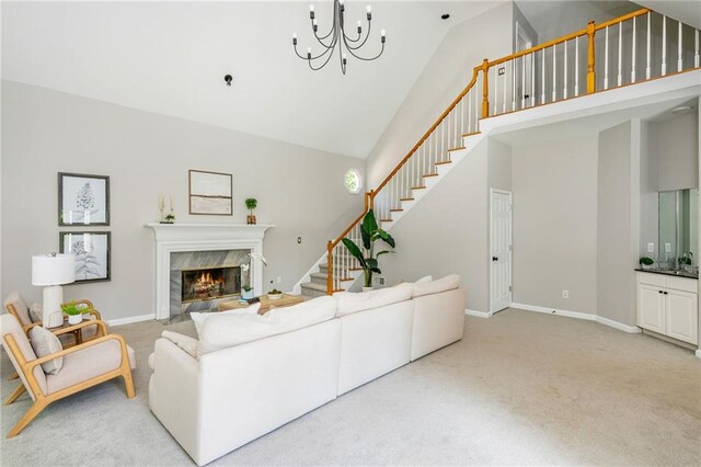 carpeted living room with a notable chandelier, a premium fireplace, high vaulted ceiling, baseboards, and stairway