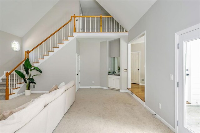 living area with visible vents, stairs, baseboards, high vaulted ceiling, and carpet