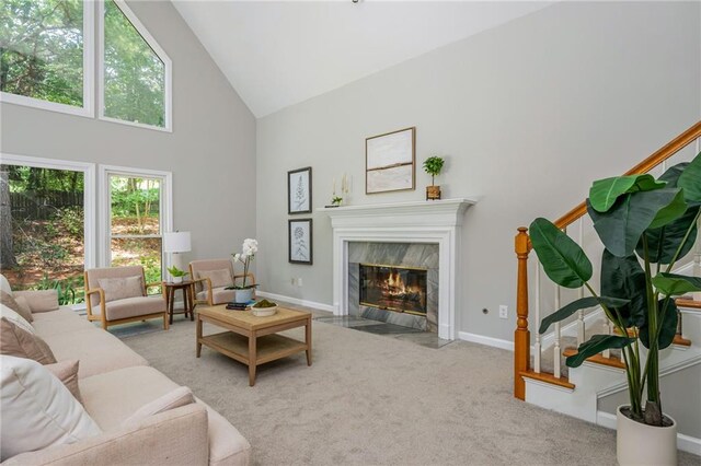 carpeted living area featuring high vaulted ceiling, baseboards, and a fireplace