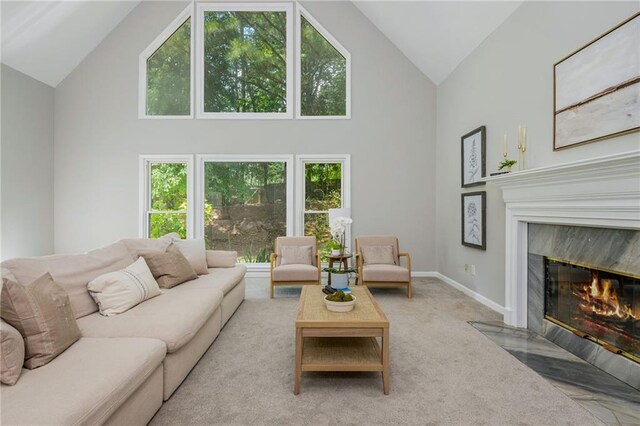 carpeted living room featuring baseboards, a fireplace, a wealth of natural light, and high vaulted ceiling
