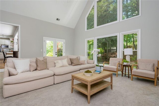 carpeted living area with high vaulted ceiling, visible vents, and a healthy amount of sunlight