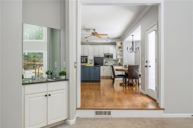 interior space with white cabinets, dark countertops, a sink, stainless steel microwave, and visible vents
