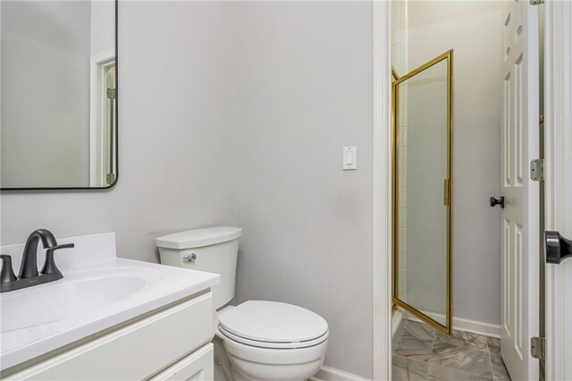 bathroom featuring vanity, toilet, baseboards, and a stall shower