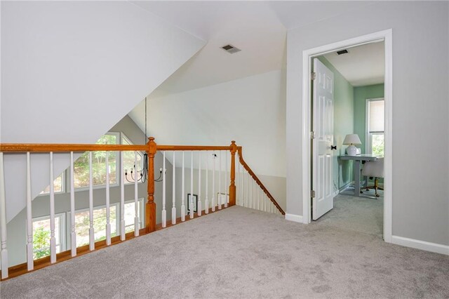 hall featuring carpet floors, baseboards, visible vents, and lofted ceiling
