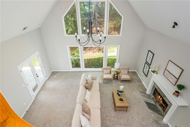 living area with carpet floors, baseboards, a notable chandelier, and high vaulted ceiling