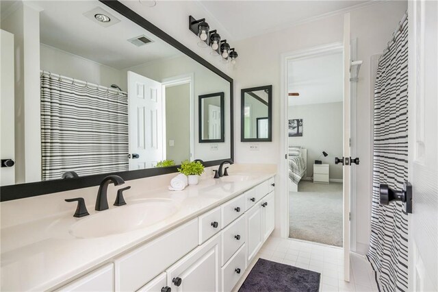 ensuite bathroom featuring a sink, tile patterned flooring, double vanity, and visible vents