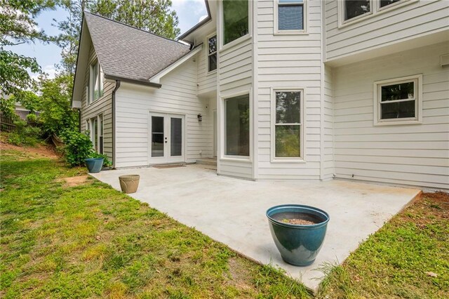 rear view of house with french doors, a lawn, a patio area, and roof with shingles