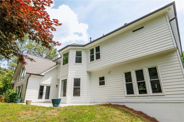 back of property with french doors and a lawn