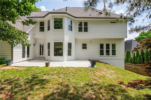back of property with a patio, a lawn, and fence