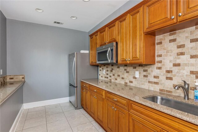 kitchen with visible vents, brown cabinets, a sink, baseboards, and stainless steel appliances