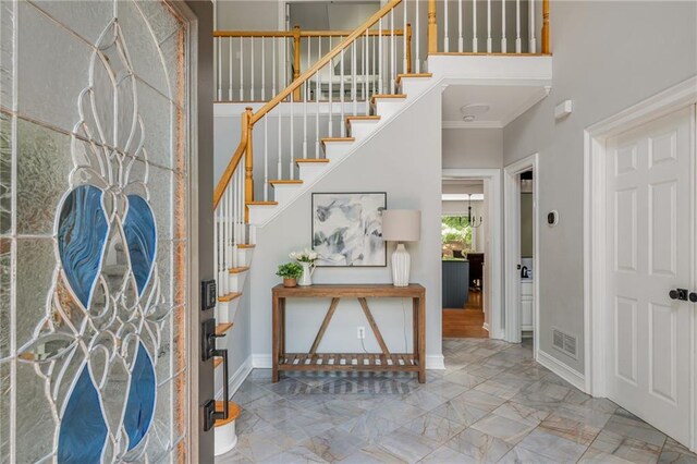 foyer featuring crown molding, baseboards, stairs, and visible vents