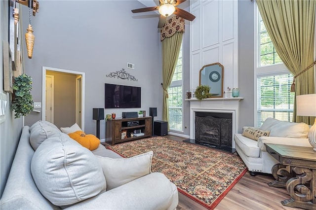 living room featuring ceiling fan, hardwood / wood-style floors, and a towering ceiling