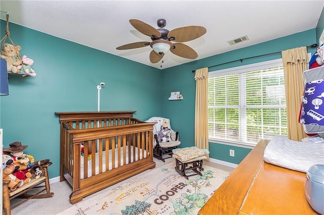 carpeted bedroom featuring a crib and ceiling fan