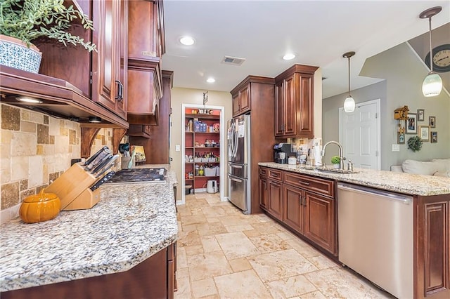 kitchen with light stone countertops, appliances with stainless steel finishes, tasteful backsplash, sink, and pendant lighting