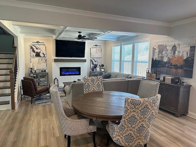 dining room featuring light wood-style flooring, stairs, ceiling fan, and a glass covered fireplace