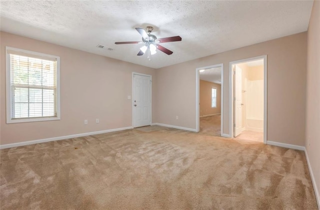 unfurnished room with a textured ceiling, light colored carpet, and ceiling fan