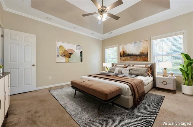 carpeted bedroom with multiple windows, ceiling fan, crown molding, and a raised ceiling