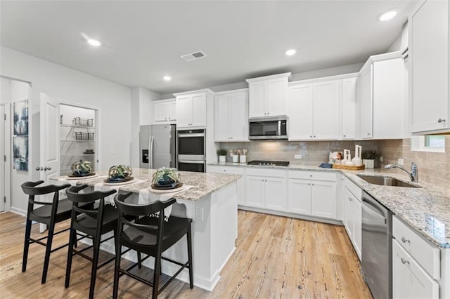 817 Dobby Way, Mcdonough, GA 30252 - kitchen with appliances with stainless steel finishes, white cabinets, a center island, a breakfast bar area, and tasteful backsplash