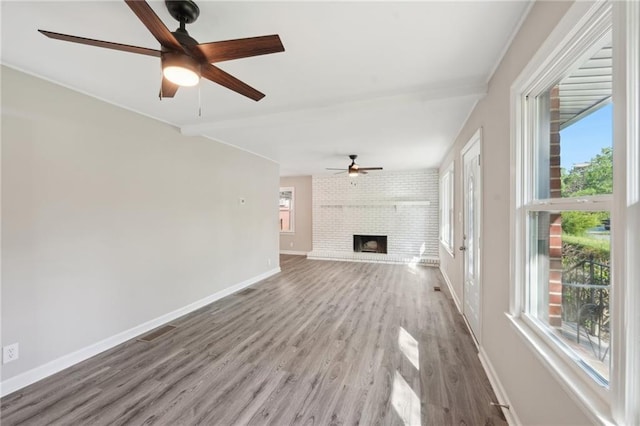 unfurnished living room with a ceiling fan, wood finished floors, baseboards, and a fireplace