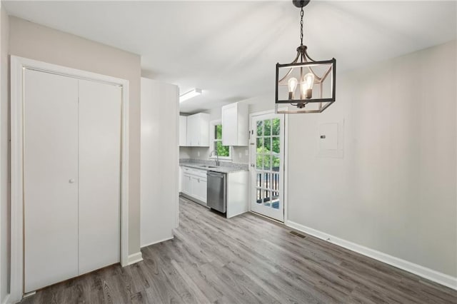 kitchen with a sink, wood finished floors, baseboards, a chandelier, and white cabinetry