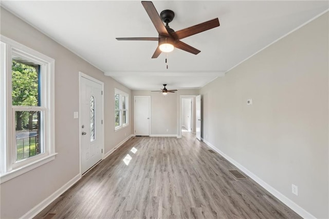 unfurnished living room featuring healthy amount of natural light, a ceiling fan, light wood-style floors, and baseboards