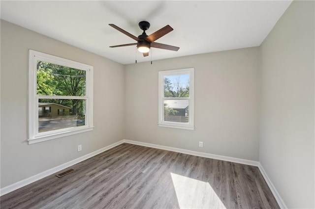 spare room with plenty of natural light, wood finished floors, baseboards, and a ceiling fan
