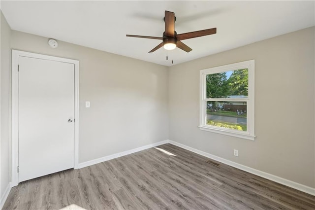 empty room with ceiling fan, wood finished floors, baseboards, and a smoke detector