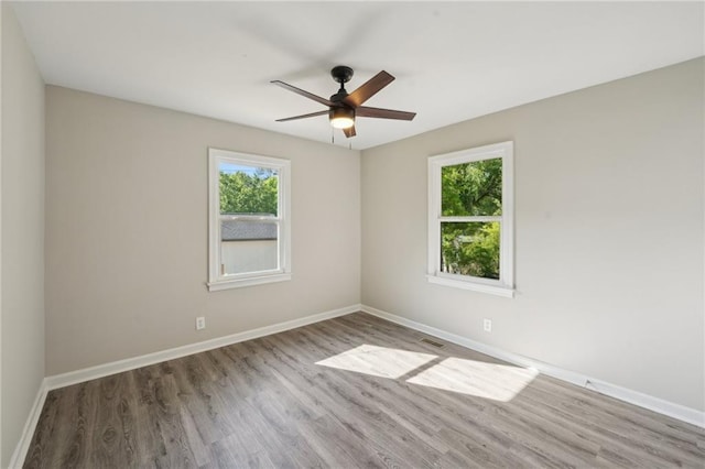 unfurnished room featuring healthy amount of natural light, ceiling fan, wood finished floors, and baseboards
