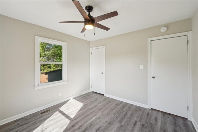 unfurnished bedroom featuring wood finished floors, baseboards, and ceiling fan