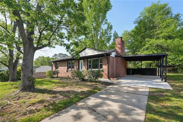 view of front facade with a chimney, concrete driveway, brick siding, and a carport