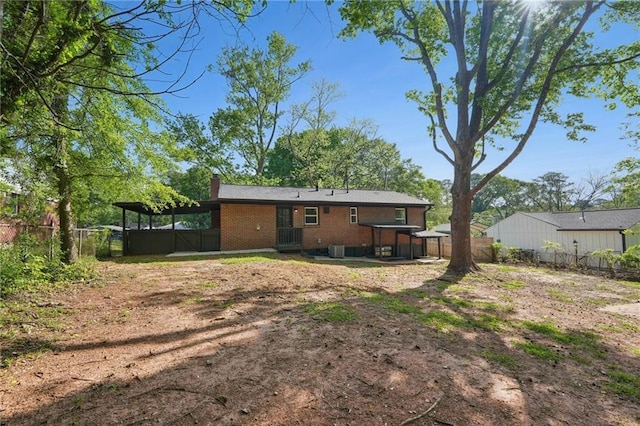 back of house featuring a chimney, a fenced backyard, and brick siding