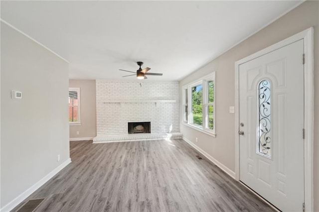 unfurnished living room with a ceiling fan, wood finished floors, baseboards, and a brick fireplace