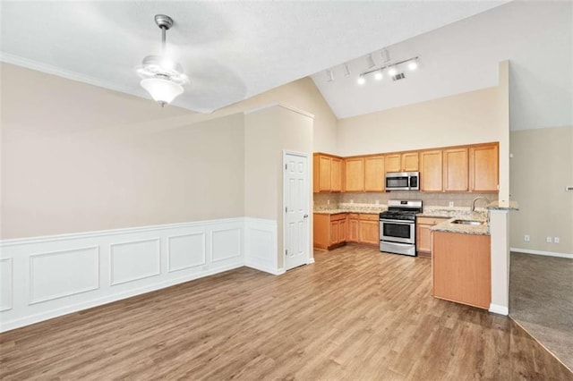 kitchen featuring stainless steel appliances, a sink, visible vents, light wood-style floors, and vaulted ceiling