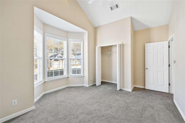 unfurnished bedroom featuring lofted ceiling, carpet floors, baseboards, and visible vents