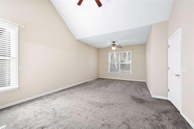 empty room with lofted ceiling, carpet floors, a ceiling fan, and baseboards