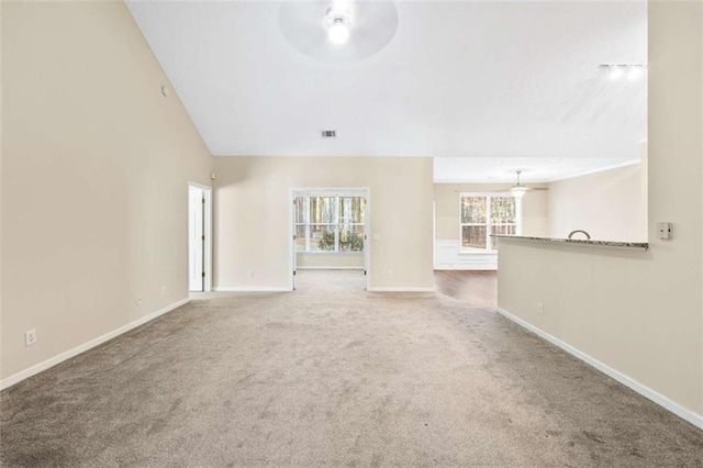 unfurnished living room featuring ceiling fan, visible vents, baseboards, vaulted ceiling, and carpet