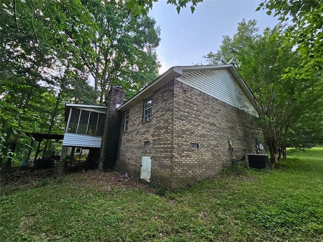 12 Lakemont Dr SE, Silver Creek, GA 30173 - view of side of home featuring a sunroom, a chimney, brick siding, central air condition unit, and a lawn