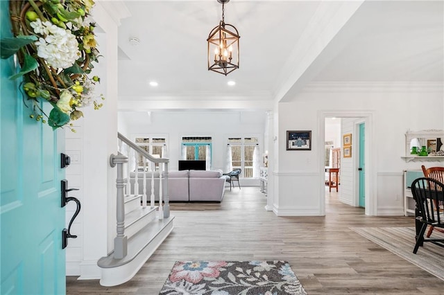 entryway with ornamental molding, a chandelier, and light wood-type flooring