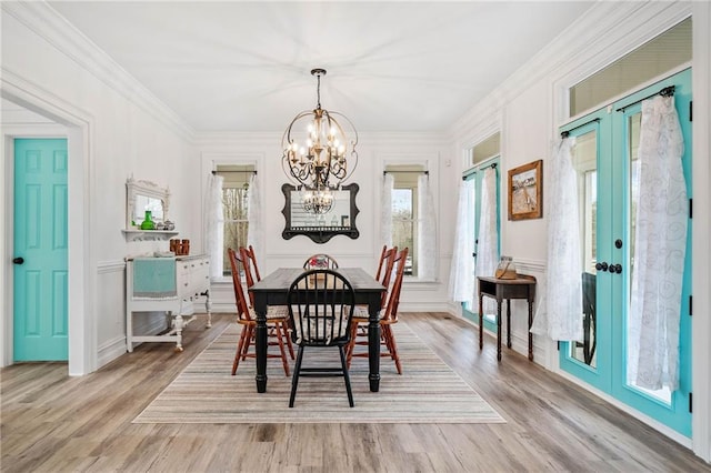 dining room featuring a notable chandelier, crown molding, light hardwood / wood-style flooring, and french doors