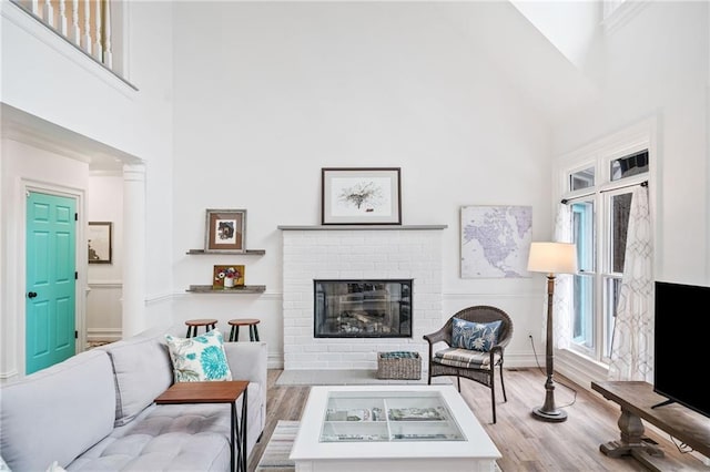 living room featuring light hardwood / wood-style floors, high vaulted ceiling, and a brick fireplace