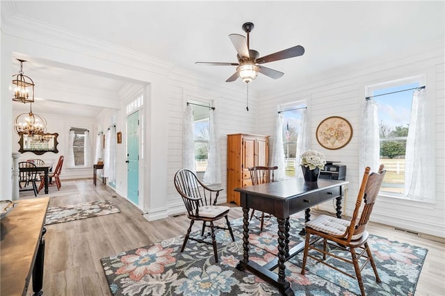 dining room with crown molding, plenty of natural light, ceiling fan with notable chandelier, and light wood-type flooring