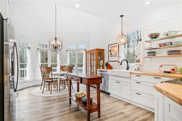 kitchen with stainless steel appliances, pendant lighting, white cabinets, and wood counters