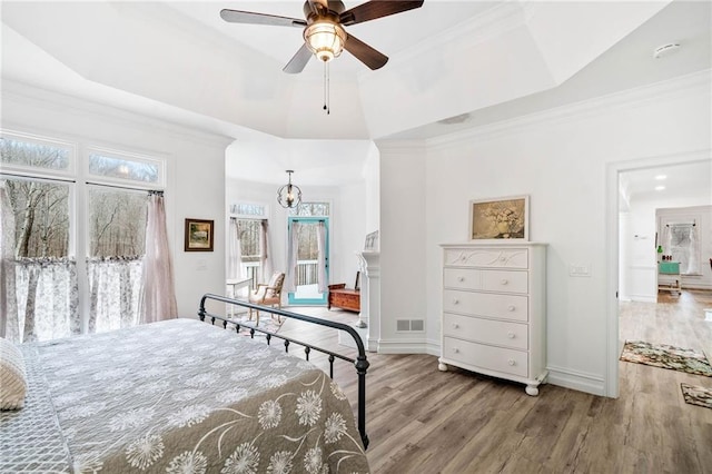 bedroom with ornamental molding, a tray ceiling, and light hardwood / wood-style flooring