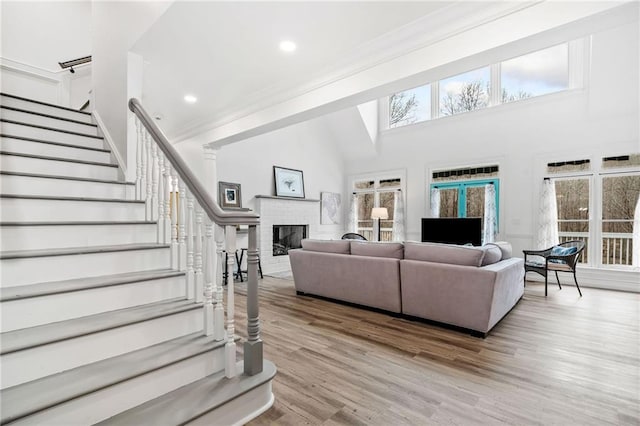 living room featuring light hardwood / wood-style flooring, a fireplace, and a high ceiling