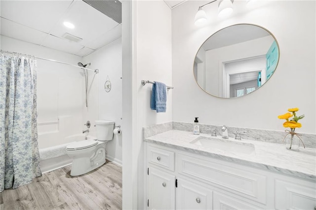 full bathroom with a paneled ceiling, hardwood / wood-style floors, shower / tub combo with curtain, vanity, and toilet