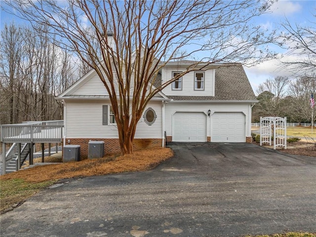 view of front property featuring a wooden deck, a garage, and central air condition unit