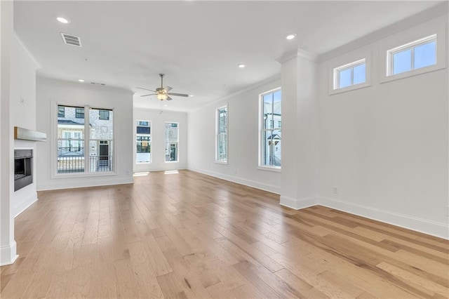 unfurnished living room featuring ceiling fan, ornamental molding, and light hardwood / wood-style floors