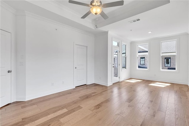 empty room with a tray ceiling, crown molding, light hardwood / wood-style flooring, and ceiling fan