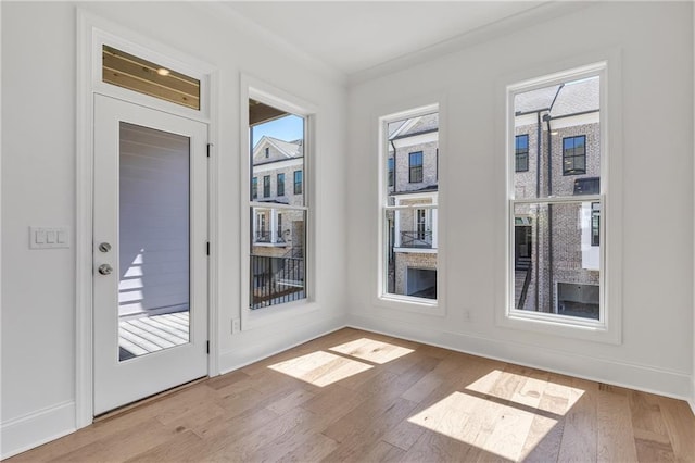 doorway with hardwood / wood-style floors, ornamental molding, and a healthy amount of sunlight